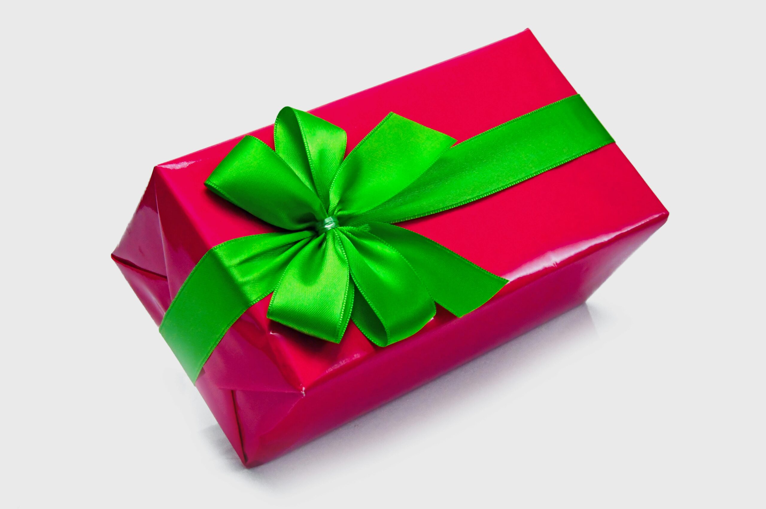 Bright red gift box wrapped with a vibrant green ribbon, perfect for festive occasions.